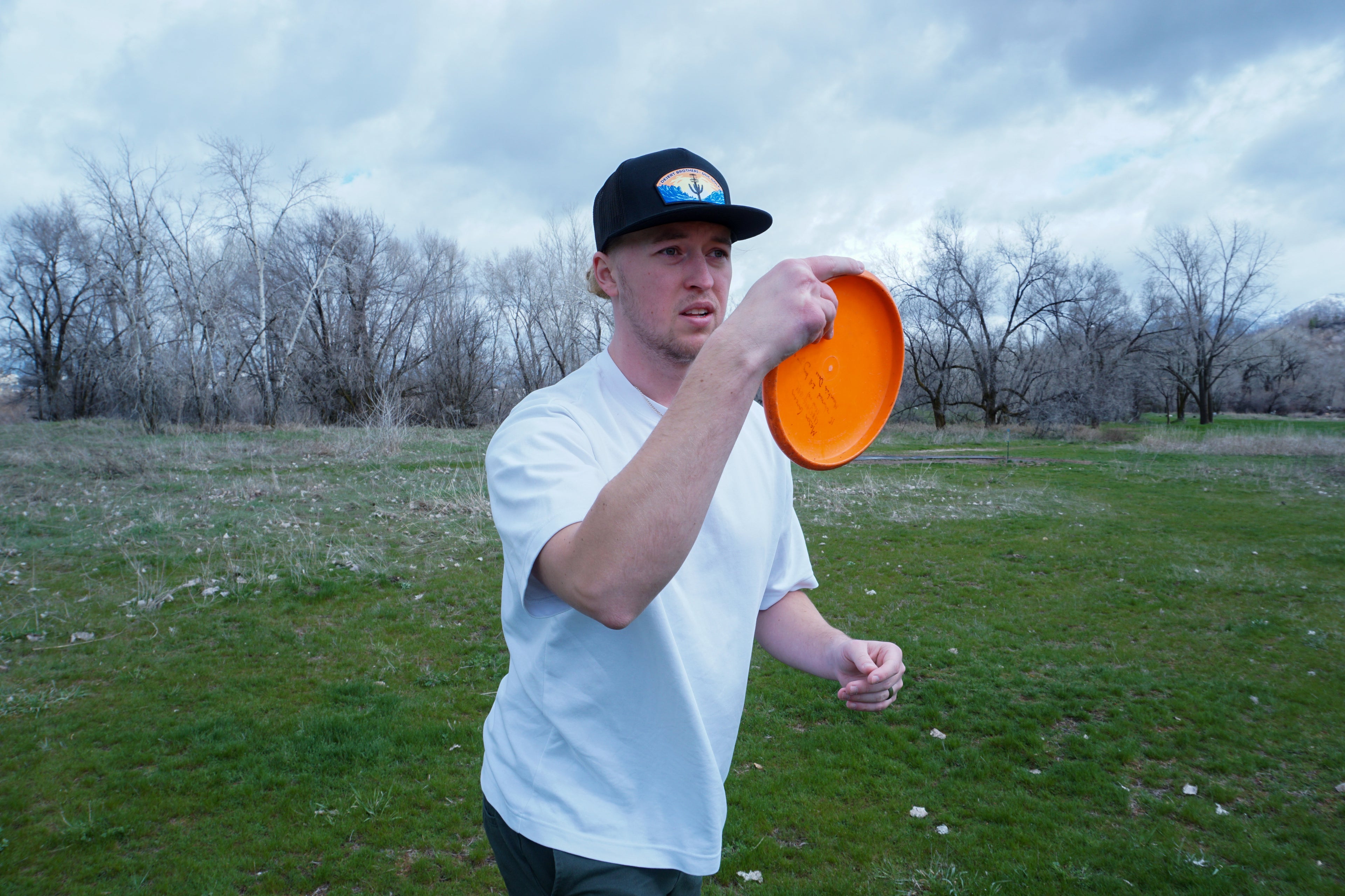 Photo of disc golf player putting. Wearing a cool Disc golf hat, made by Desert Brothers